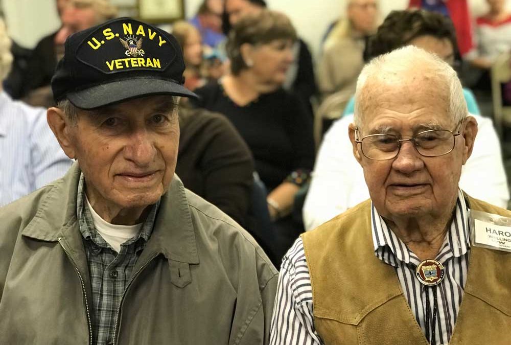 two veterans sitting in a crowd