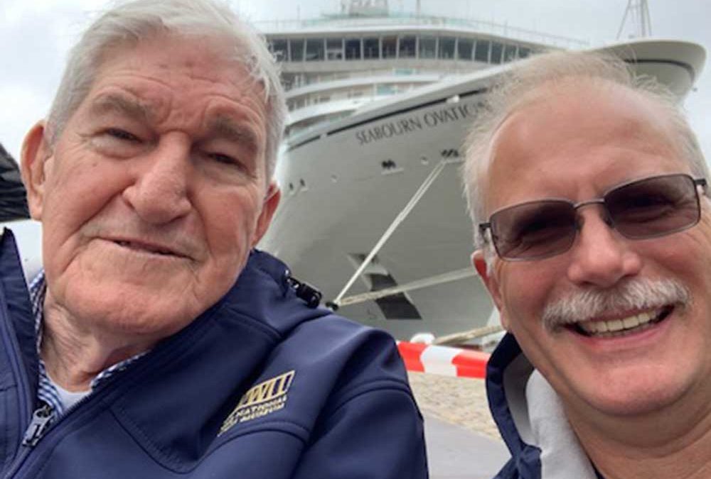 two veterans standing in front of cruise ship