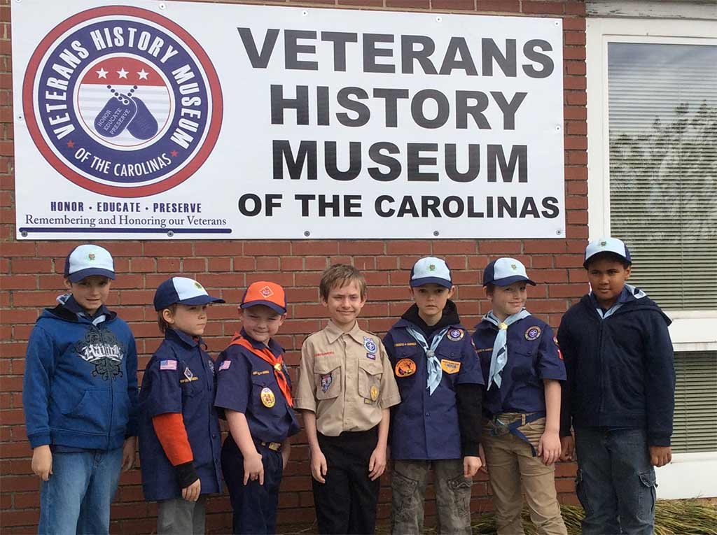 group of boy scouts in front of the museum sign
